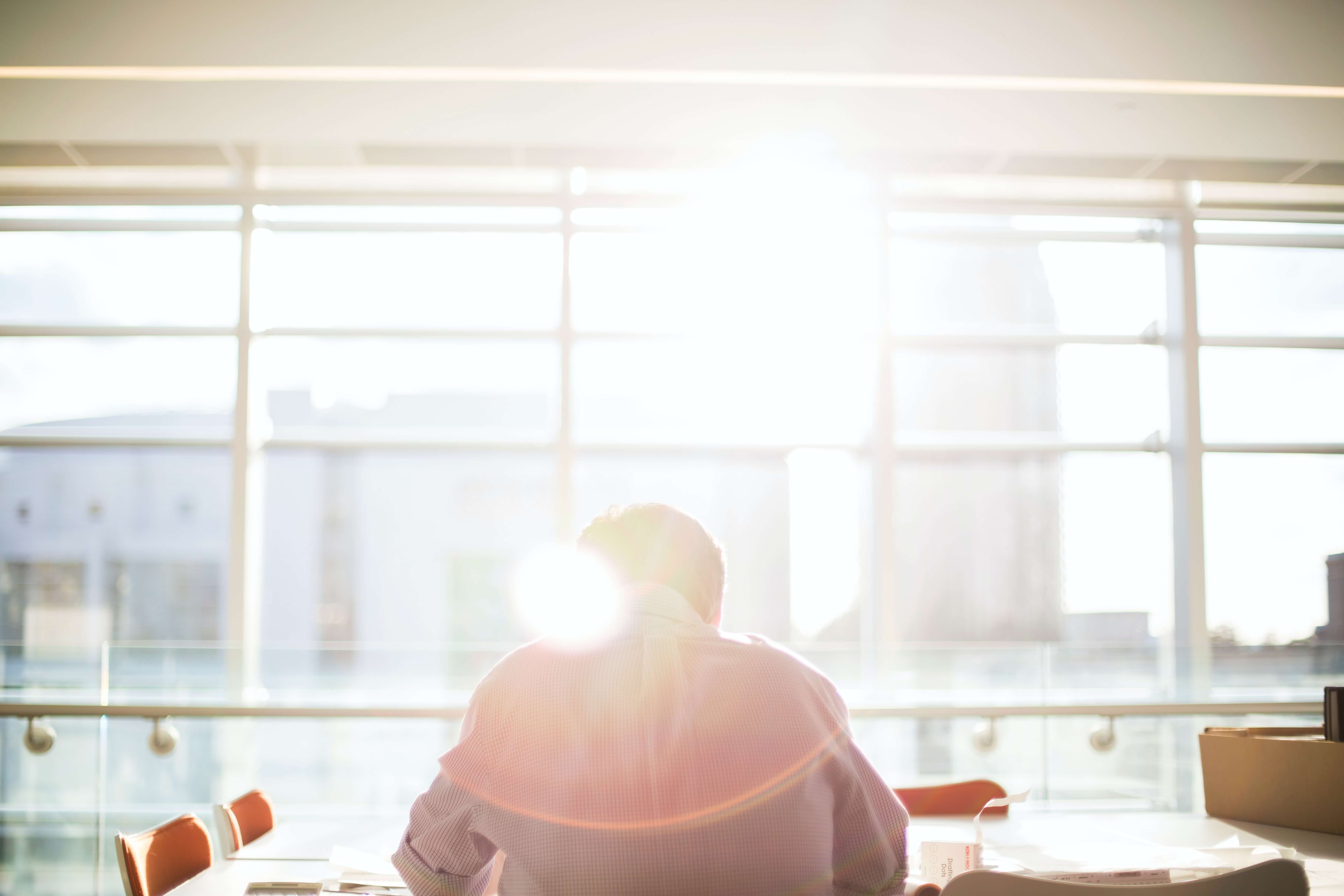 Man hunched over table with sunlight coming through window