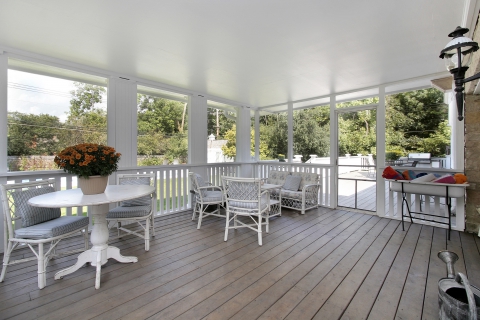 Screened-in patio with white wood flooring and white wicker furniture