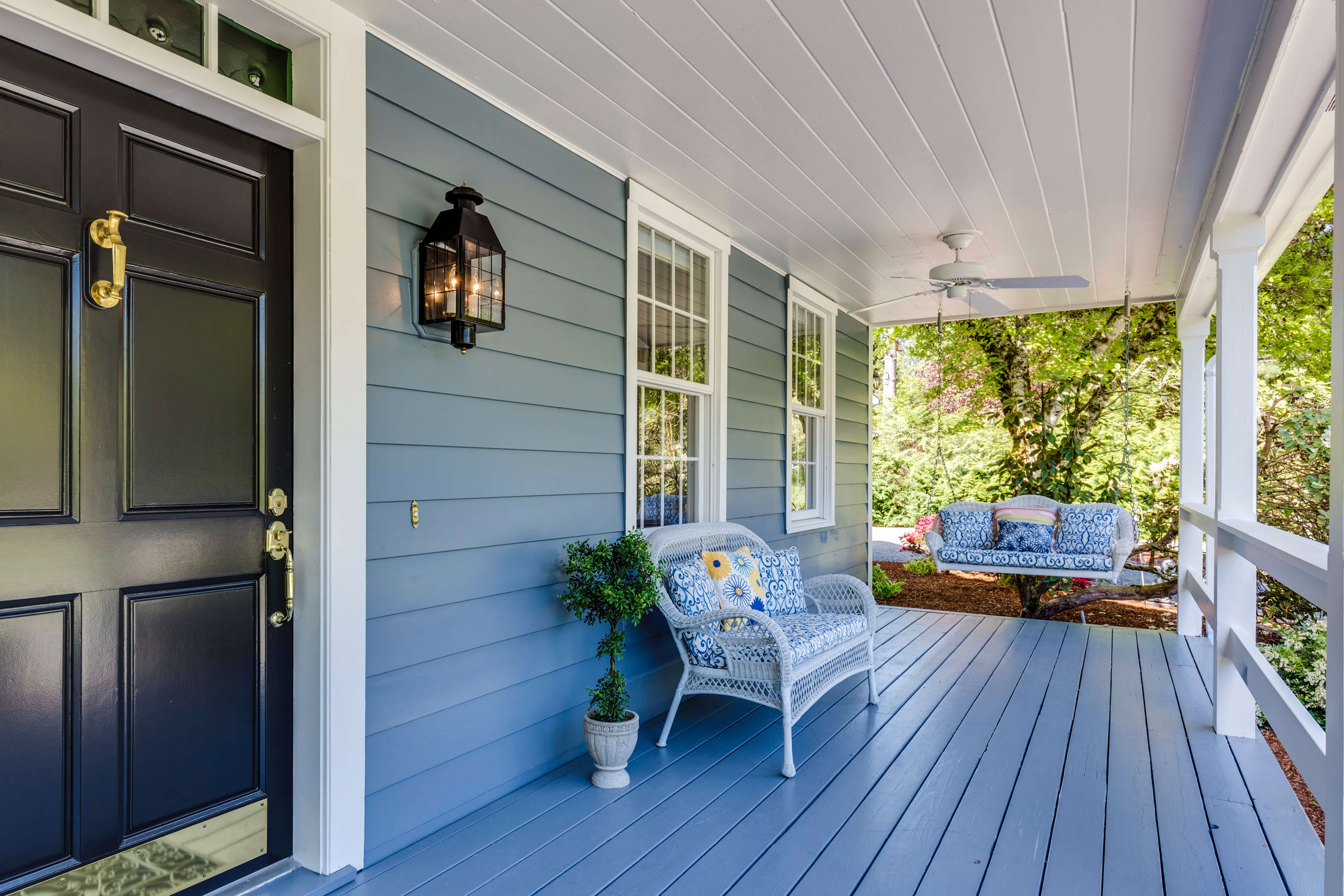 Front porch with a swing, blue siding, and white trim