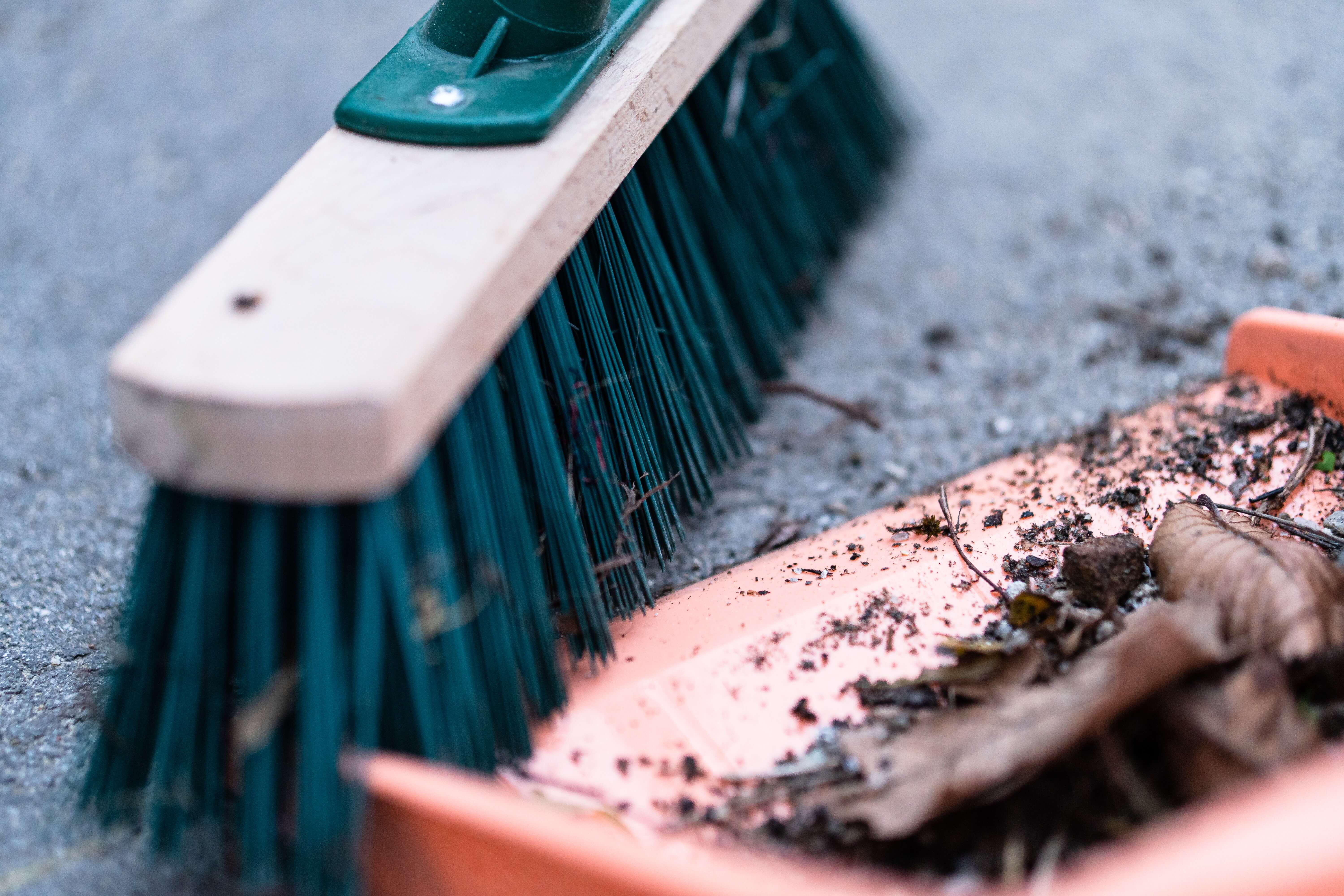 Broom pushing debris into a dustpan