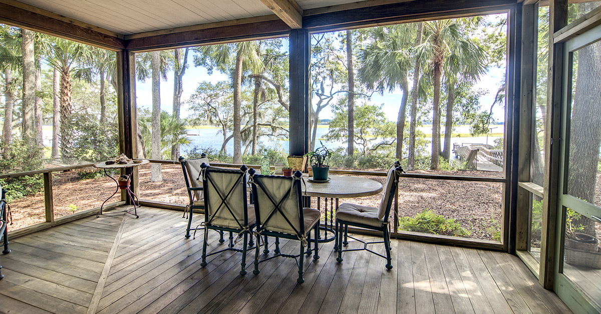 Screened-in porch with view of the waterfront, wood trim, and wood flooring