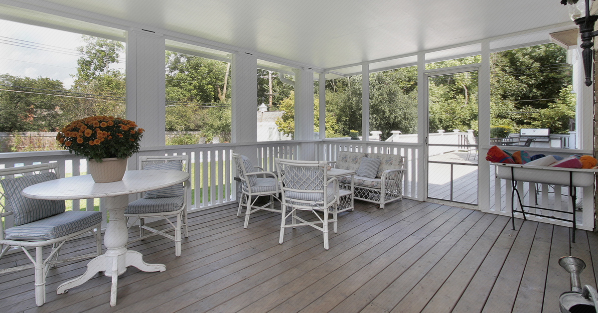 Screened-in porch with white wood flooring and white wicker furniture