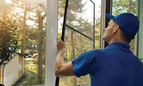 Man installing a clean window screen into a window